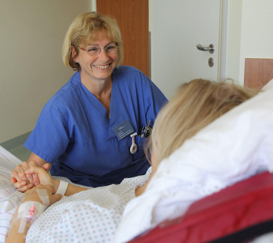 Sankt-Joseph-Stift-Mitarbeiterin hält die Hand einer Patientin
